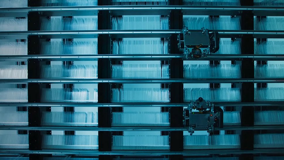 Wide view of Microsoft Project Silica’s robotic data library with multiple racks holding quartz glass storage plates and automated retrieval units.