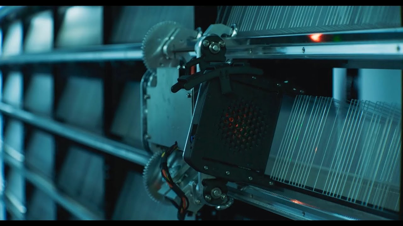 Robotic arm handling quartz glass storage plates inside Microsoft Project Silica’s automated data library system.